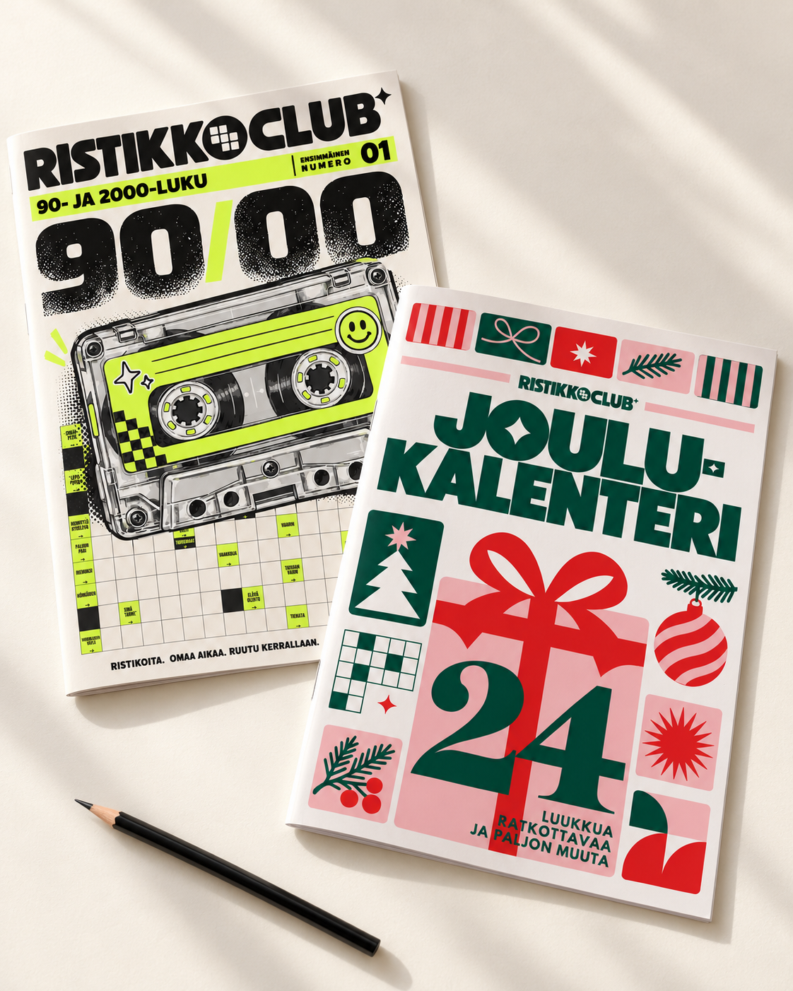 Ristikko Clubin ensimmäinen numero ja joulukalenterilehti kynän vieressä luonnonvalossa